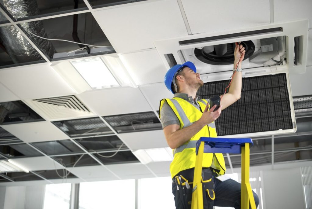 electrician fitting air conditioning to office interior